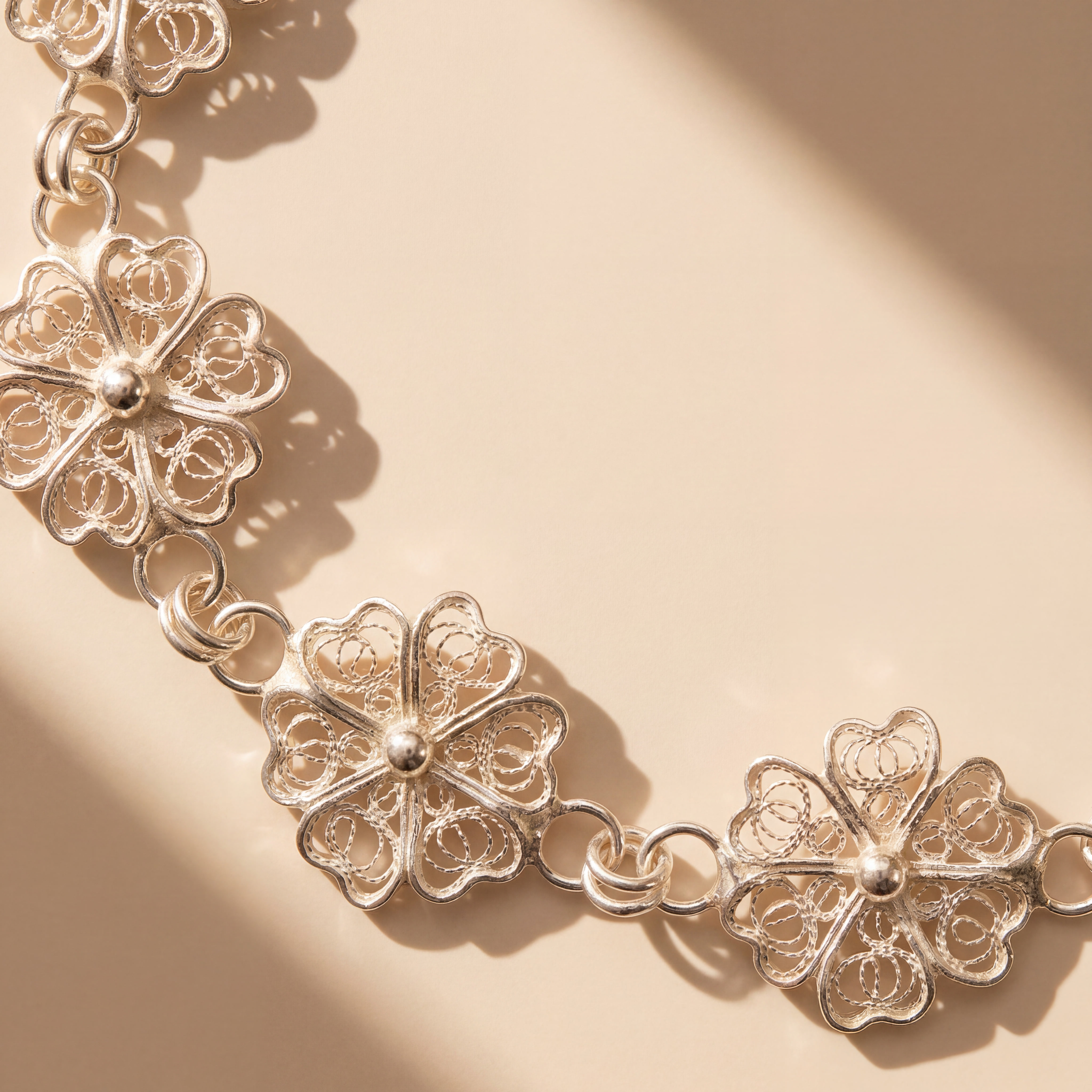 A bracelet of filigree flowers lying across warm light and shadow