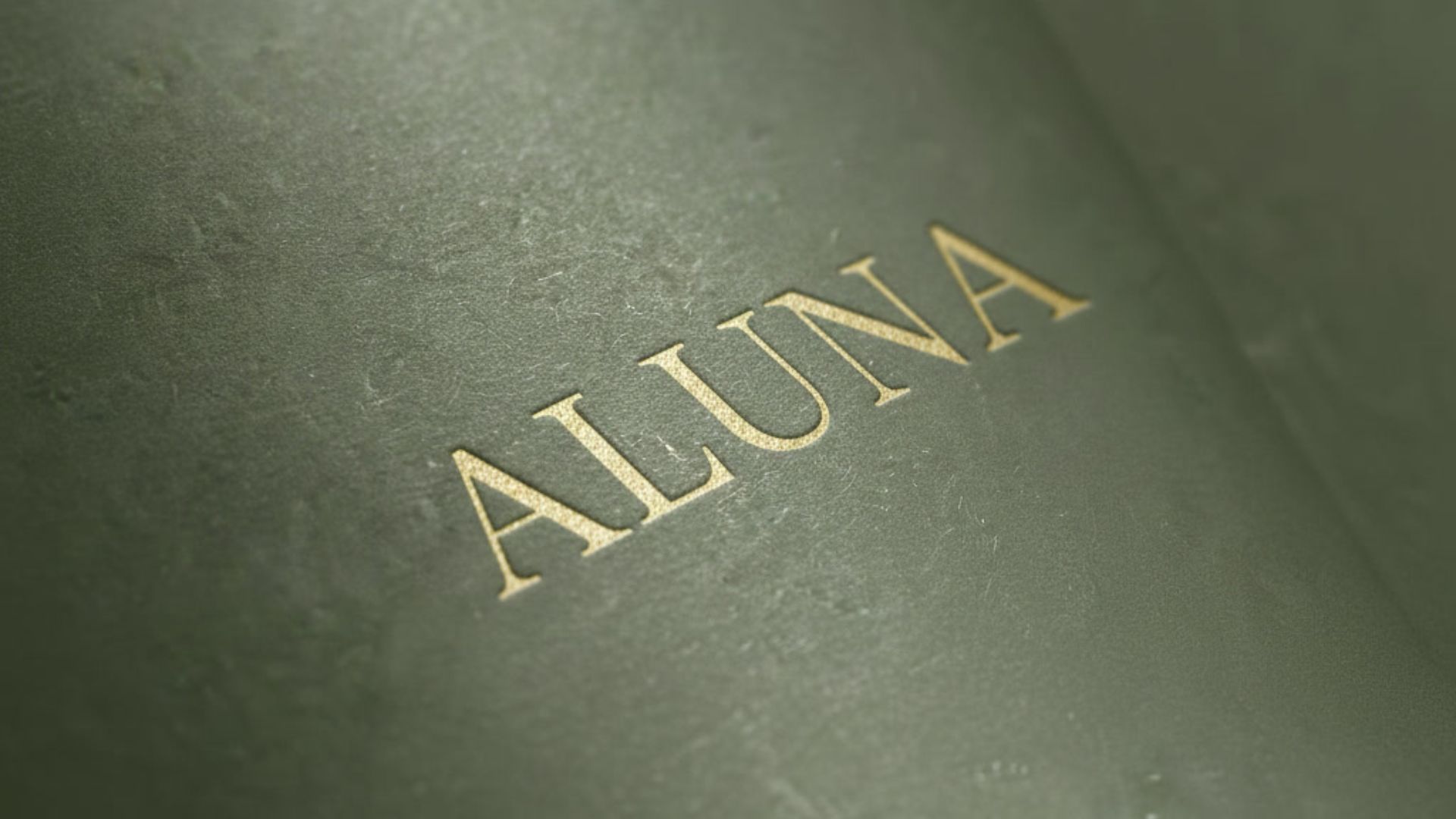 ALUNA logotype embossed in gold on dark green leather